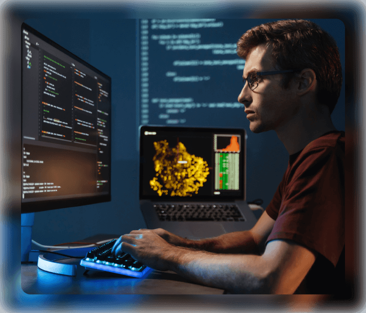 abstract blurred image behind a man working on a desktop computer and a laptop