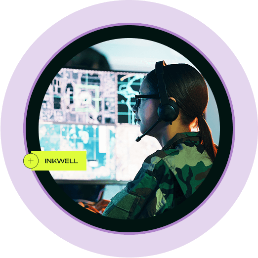a military soldier working on a computer and wearing a headset with the text "inkwell" next to her